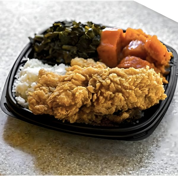 Island Crave's fried chicken with rice, collard greens, and candied yams in a black takeout container.