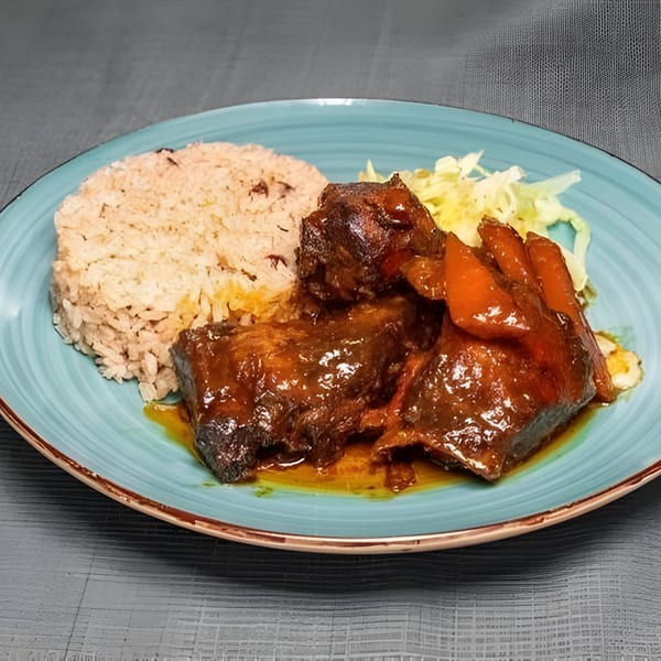 Island Crave's brown stew chicken with rice and peas, and shredded cabbage on a blue plate.