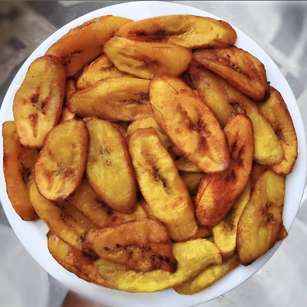 A white plate filled with golden-brown fried plantain slices from Island Crave.
