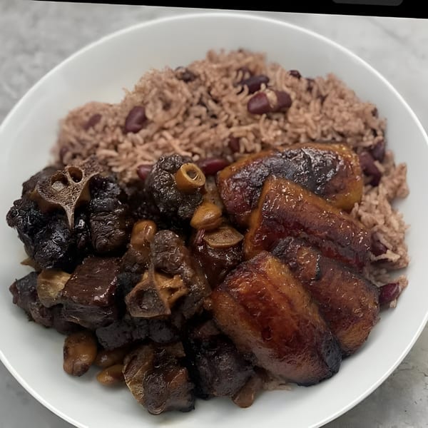 Island Crave's oxtail stew with rice and peas, and fried plantains on a white plate.